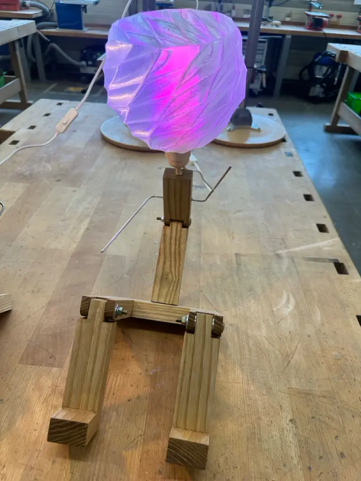 Foto: Roboterlampe aus Holz mit lila 3D-gedrucktem Schirm auf einer Werkbank